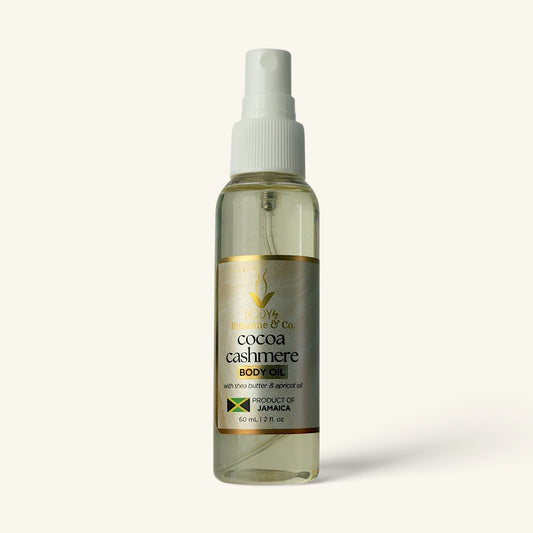 A 60 mL spray bottle of Body Wave & Co. Cocoa Cashmere Body Oil, featuring a white spray nozzle and a gold and black label, set against a solid off-white background.