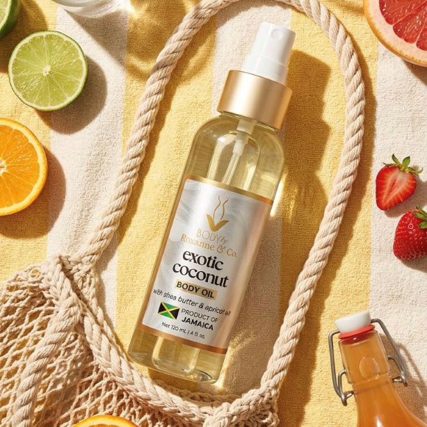 A bottle of Body & Breeze Co. Exotic Coconut Body Oil is styled in a flat-lay composition on a yellow towel, surrounded by a woven rope bag, citrus slices, strawberries, and a glass bottle.