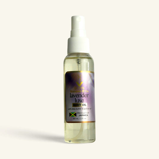 A 60 mL spray bottle of Lavender Luxe Hair & Oil by The Beauty Brand, featuring a white spray nozzle and a purple label with gold and green accents, set against a solid off-white background.