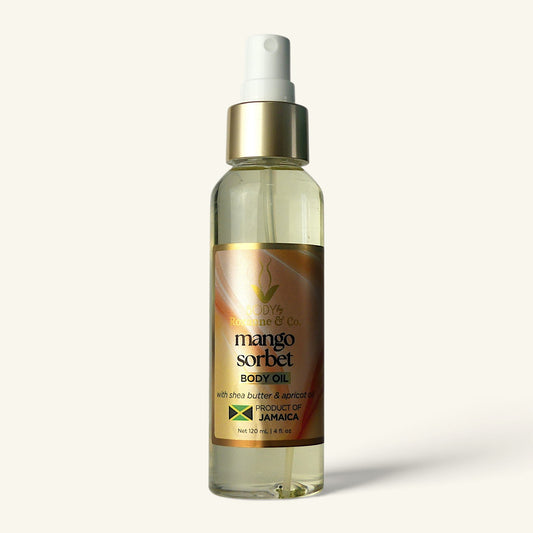 A clear plastic spray bottle of Mango Sorbet Body Oil with a white pump dispenser and a gold label, set against a solid off-white background.