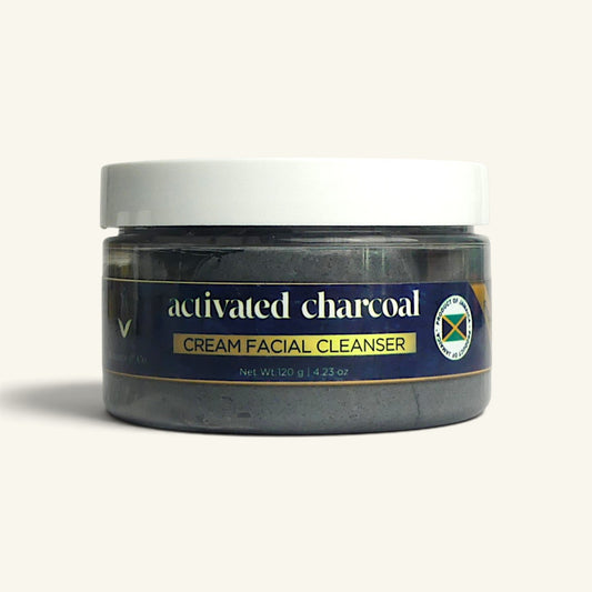 A jar of Activated Charcoal Cream Facial Cleanser on a light beige background. The jar is filled with dark charcoal powder and has a white lid with a dark blue label featuring gold and white text.