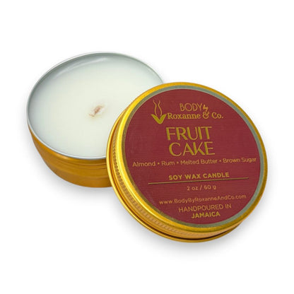 Scented candle in a tin labeled 'Fruit Cake' by Body by Roxanne & Co on a white background