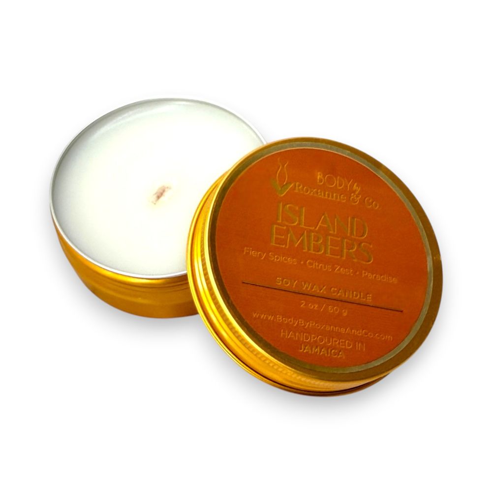 Candle in a metallic tin labeled 'Island Embers' on a white background