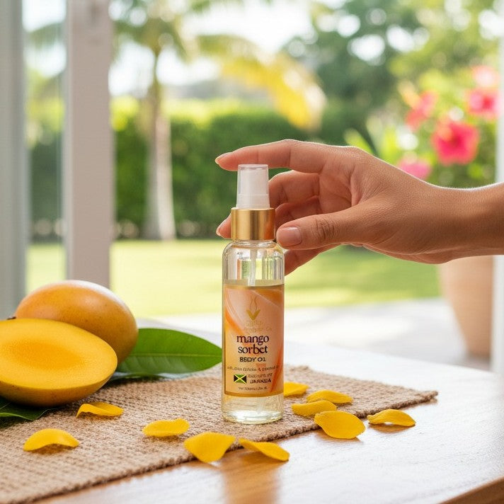 Hand holding a bottle of mango sorbet body oil with mangoes and petals on a table outdoors.