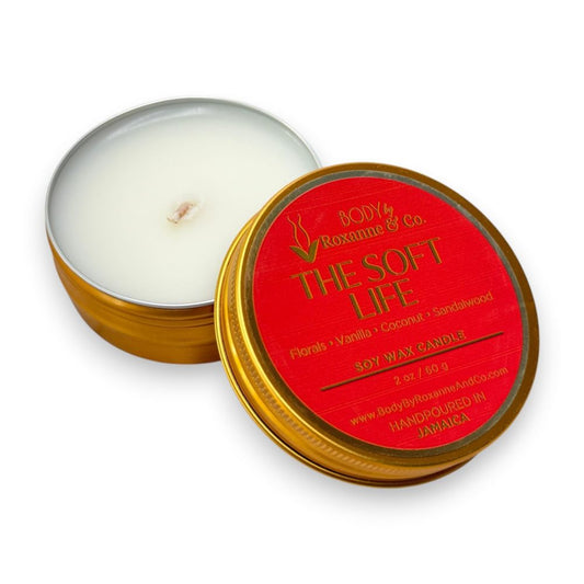Scented candle in a tin with a red lid featuring branding on a white background