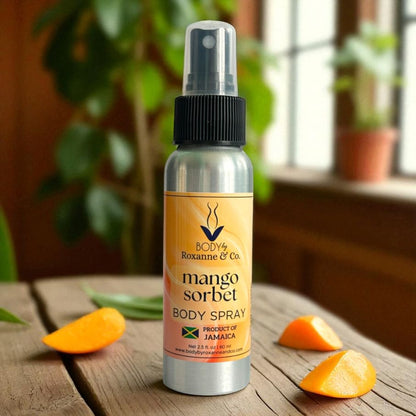 Body spray bottle labeled 'mango sorbet' on a wooden surface with orange slices and green leaves.
