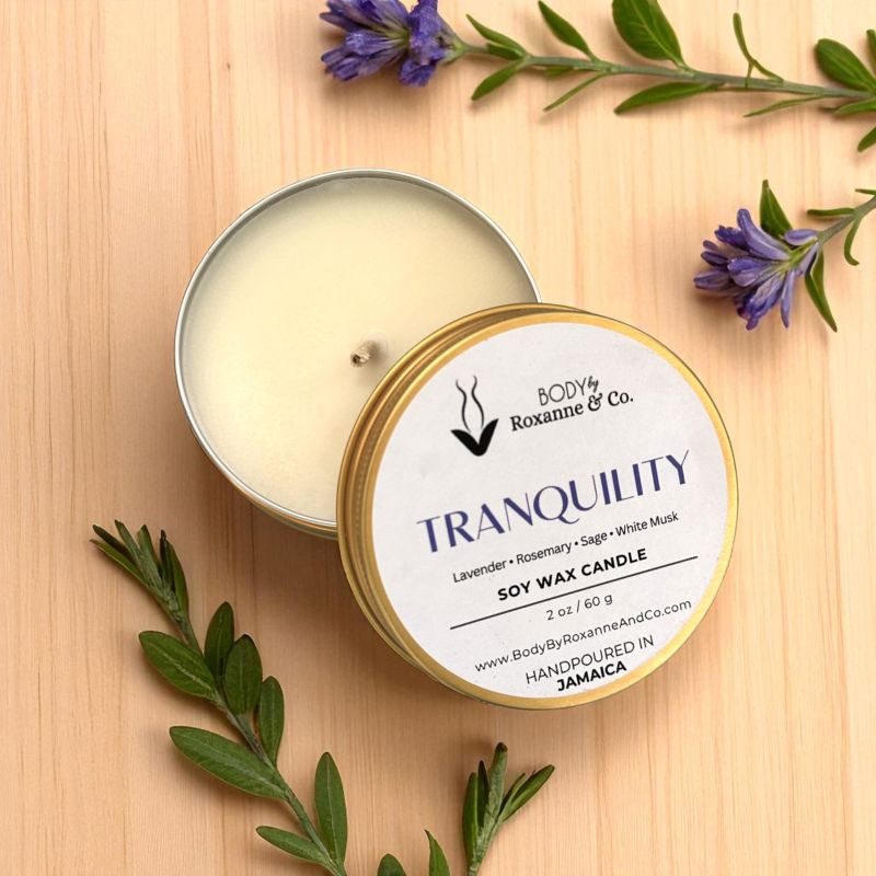 Body & Co Tranquility soy wax candle in a tin on a wooden surface with lavender leaves.